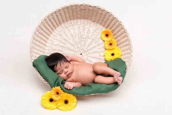 Bonito recém-nascido misto raça bebê dormindo na cesta perto de flores no branco — Fotografia de Stock