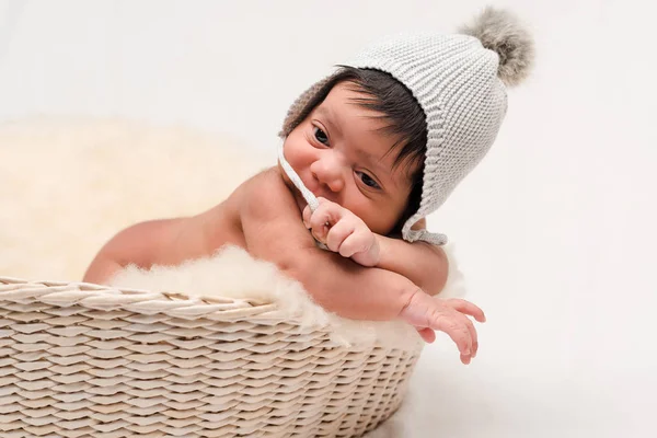 Cute newborn mixed race baby touching knitted hat on white — Stock Photo