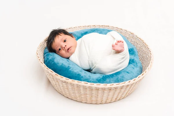 Мила новонароджена змішана раса дитини, загорнута в ковдру, лежить в кошику на білому — стокове фото