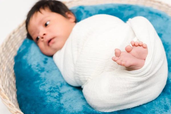 Foco seletivo do bebê recém-nascido misto envolto em cobertor deitado em cesta — Fotografia de Stock