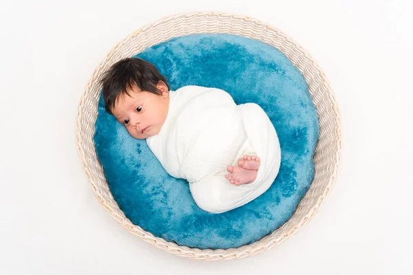 Top view of newborn mixed race baby wrapped in blanket lying in basket isolated on white — Stock Photo