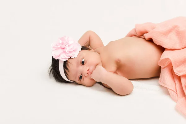 Мила змішана раса новонароджена дитина в пов'язці, лежить на білому — стокове фото