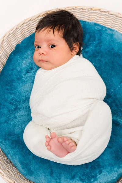 Вид зверху мила новонароджена змішана раса дитини, загорнута в ковдру, лежить в кошику ізольована на білому — стокове фото