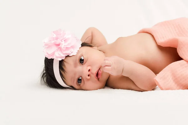 Adorable bi-racial newborn baby in headband lying on white — Stock Photo