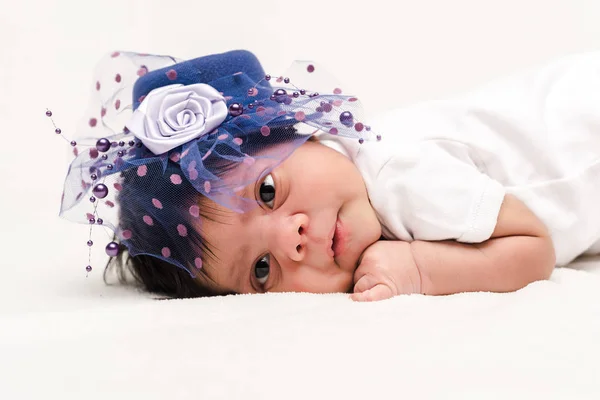 Adorable bi-racial newborn baby in blue hat lying on white — Stock Photo