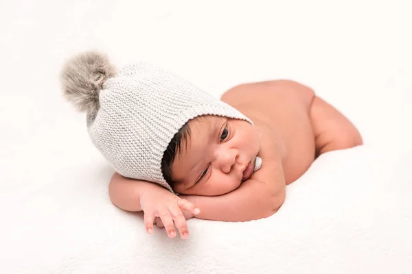 Cute mixed race newborn baby in knitted hat lying isolated on white — Stock Photo