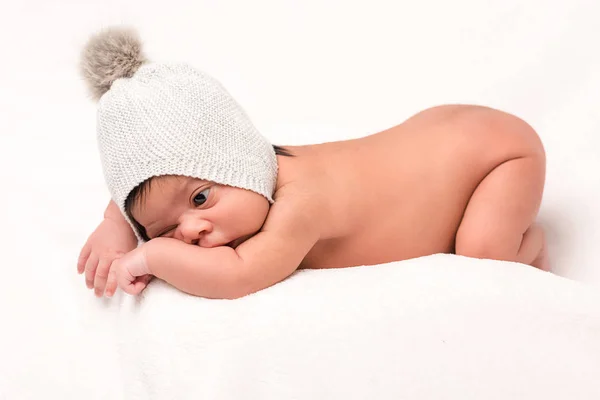 Очаровательный ребенок смешанной расы в вязаной шляпе лежал на белом — стоковое фото