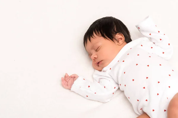 Overhead view of bi-racial newborn in baby romper sleeping isolated on white — Stock Photo