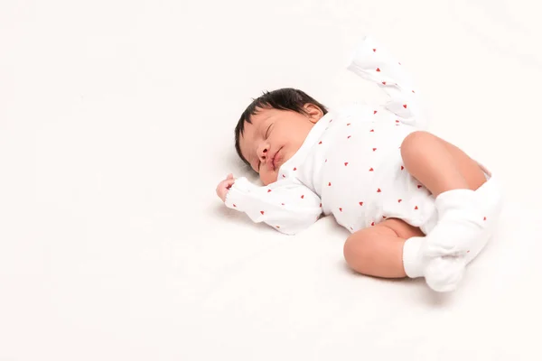 Cute bi-racial newborn in baby romper and socks sleeping on white — Stock Photo