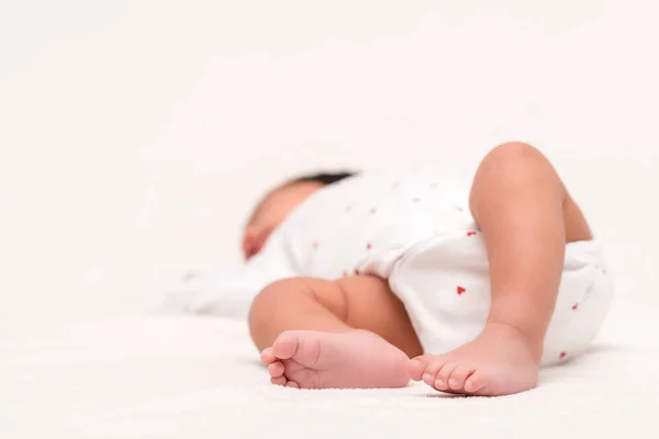 Foyer sélectif de nouveau-né mignon dans la barboteuse et chaussettes de bébé couché sur blanc — Photo de stock