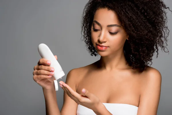 Mujer afroamericana con botella de loción, aislada en rosa — Stock Photo