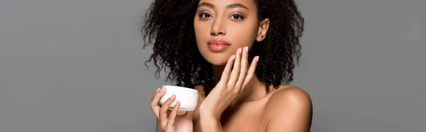 Panoramic shot of nude african american girl applying face cream, isolated on grey — Stock Photo