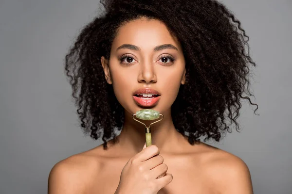 Nu afro-américaine fille à l'aide de jade rouleau, isolé sur gris — Photo de stock