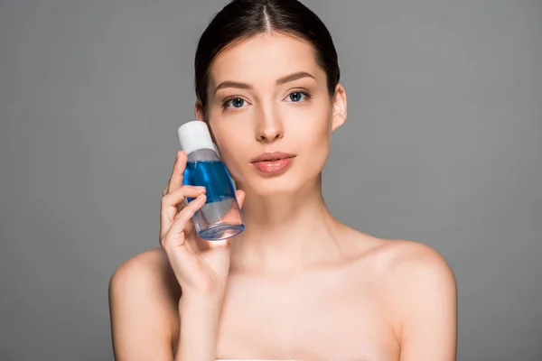 Femme nue tenant bouteille de démaquillant, isolé sur gris — Photo de stock