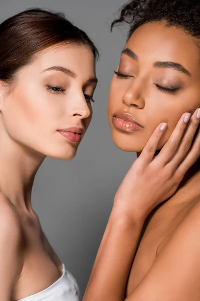 Portrait of tender multicultural women with closed eyes, isolated on grey — Stock Photo