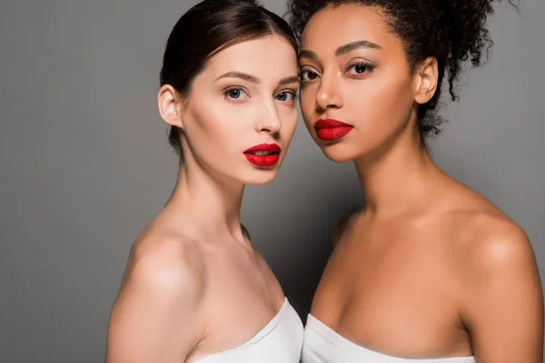 Atractivas mujeres multiculturales con labios rojos, en gris - foto de stock