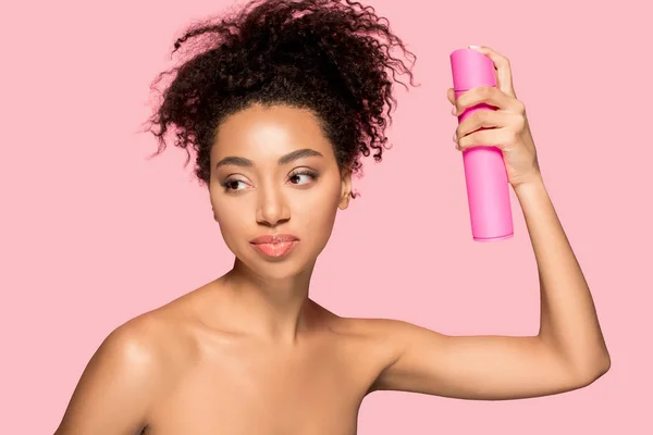 Chica afroamericana desnuda con botella de spray para el cabello, aislado en rosa - foto de stock