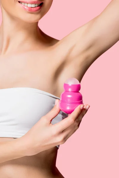 Cropped view of smiling girl applying roll deodorant, isolated on pink — Stock Photo