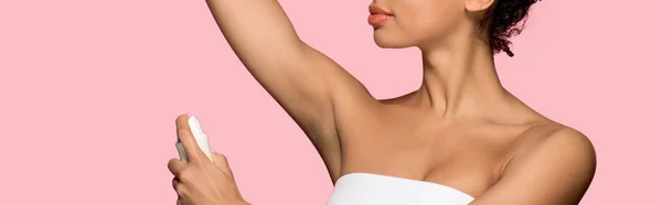 Vista recortada de chica afroamericana usando desodorante en aerosol, aislado en rosa, plano panorámico - foto de stock