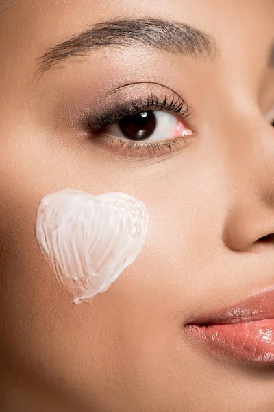 Primer plano de chica afroamericana con corazón de crema de mejilla, aislado en rosa - foto de stock