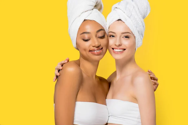 Meninas multiculturais felizes com toalhas na cabeça, isolado em amarelo — Fotografia de Stock