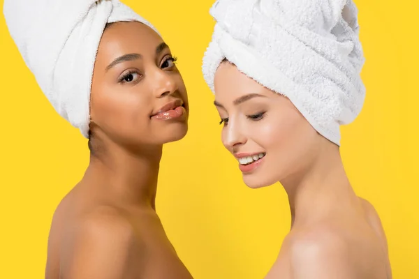 Niñas multiculturales alegres con toallas en la cabeza, aislado en amarillo - foto de stock