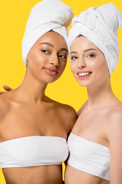 Niñas multiétnicas alegres con toallas en la cabeza, aislado en amarillo - foto de stock