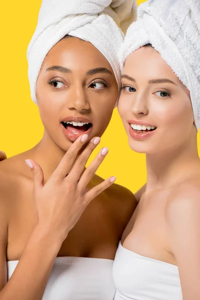 Surprised multicultural girls with towels on heads, isolated on yellow — Stock Photo