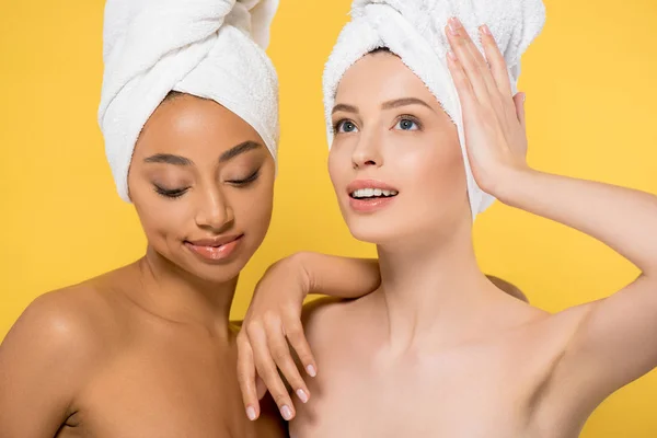 Multiethnic young woman with towels on heads, isolated on yellow — Stock Photo