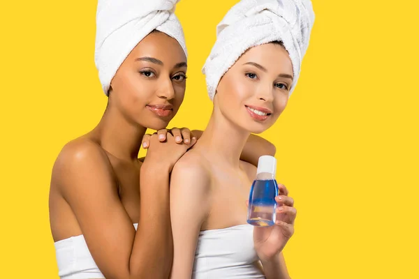 Meninas multirraciais bonitas segurando removedor de maquiagem, isolado no amarelo — Fotografia de Stock