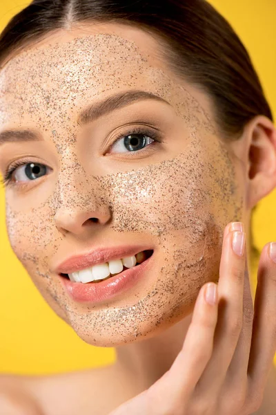 Portrait de jeune femme heureuse appliquant masque peeling, isolé sur jaune — Photo de stock