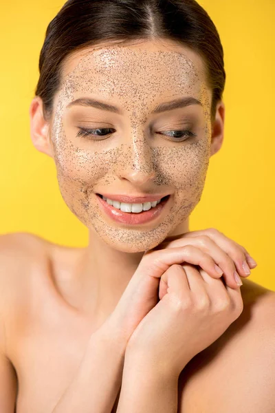 Lächelnde junge Frau mit Peeling-Maske, isoliert auf gelb — Stockfoto