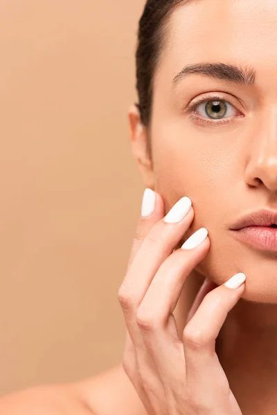 Vue recadrée de fille touchant visage propre et regardant la caméra isolée sur beige — Photo de stock