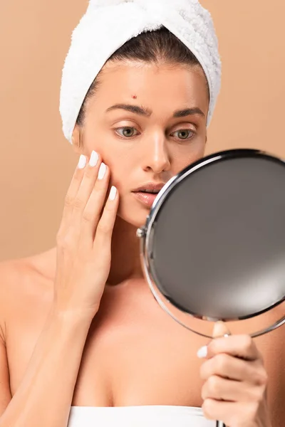 Selective focus of young woman with pimple on face looking at mirror isolated on beige — Stock Photo