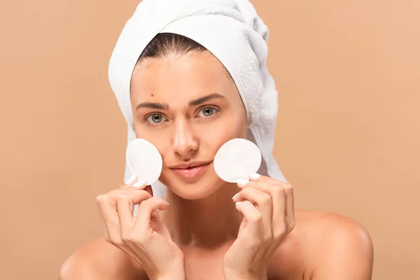 Happy naked woman with pimple on face holding cotton pads isolated on beige — Stock Photo