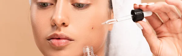 Panoramic shot of woman applying serum on face with pimple isolated on beige — Stock Photo