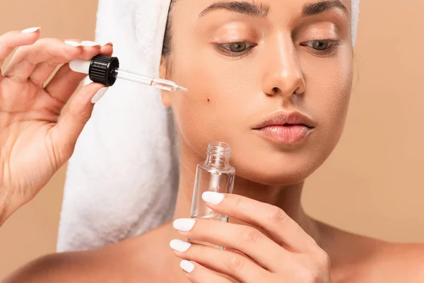 Young naked woman applying serum on face with pimples isolated on beige — Stock Photo