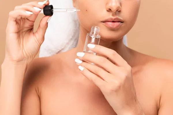 Vista cortada de jovem mulher nua aplicando soro no rosto com espinha isolada no bege — Fotografia de Stock