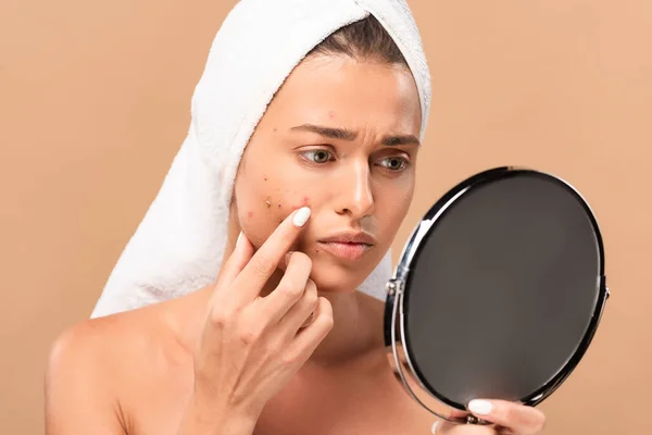 Aufgeregt nackte Mädchen in Handtuch berühren Akne im Gesicht und Blick auf Spiegel isoliert auf beige — Stockfoto