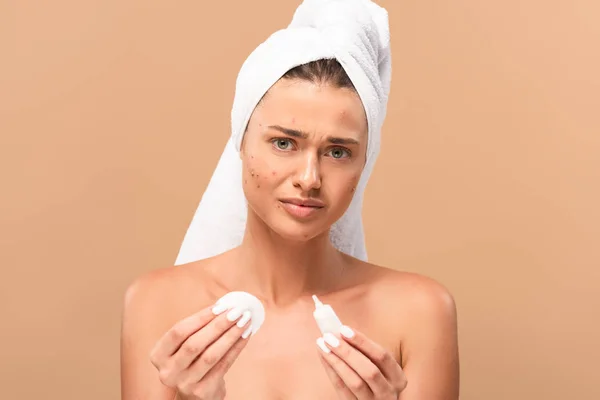 Frustrated girl with acne on face holding cotton pads isolated on beige — Stock Photo