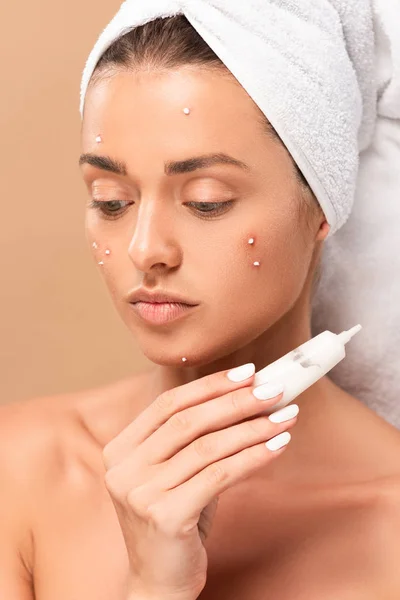 Naked girl with acne on face holding tube with treatment cream isolated on beige — Stock Photo