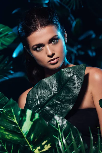 Sexy young woman looking at camera near fresh leaves — Stock Photo