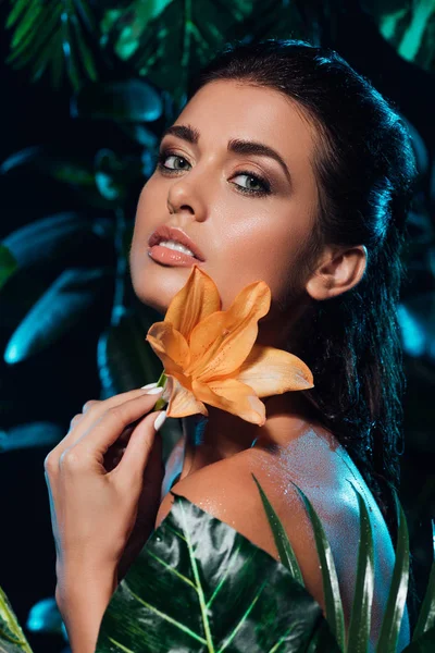 Young beautiful woman holding orchid near green leaves — Stock Photo