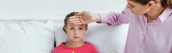 Tiro panorâmico da mãe que toca a testa da filha doente com febre — Fotografia de Stock