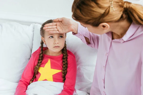 Worried mother touching forehead of ill daughter with fever — Stock Photo