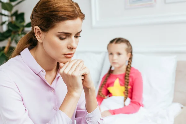 Worried mother sitting near diseased daughter in bed — Stock Photo