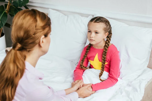 Attraente madre che si tiene per mano con figlia malata a letto — Foto stock