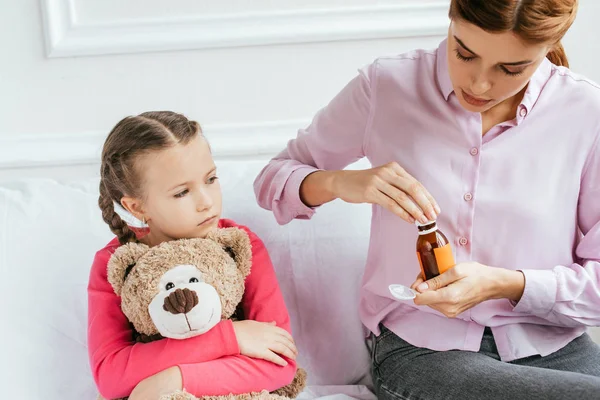 Mutter gibt kranker Tochter mit Teddybär Sirup — Stockfoto
