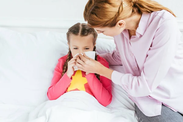 Worried mother giving napkin to sick daughter with runny nose — Stock Photo