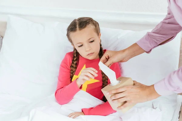 Mother giving napkins to ill daughter with runny nose — Stock Photo